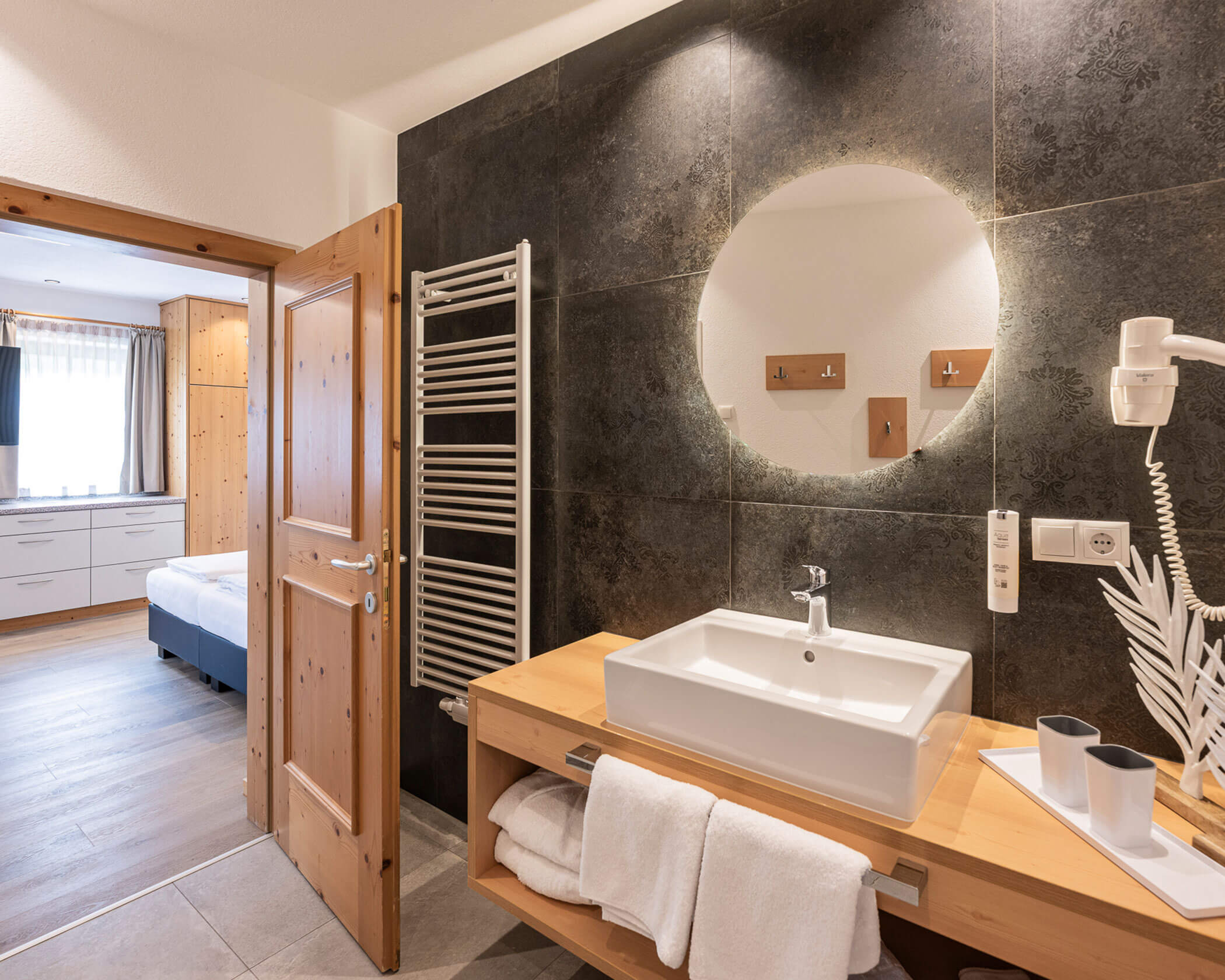 Badezimmer mit rundem Spiegel und Waschbecken im Apartment Typ A - Hotel Anewandter