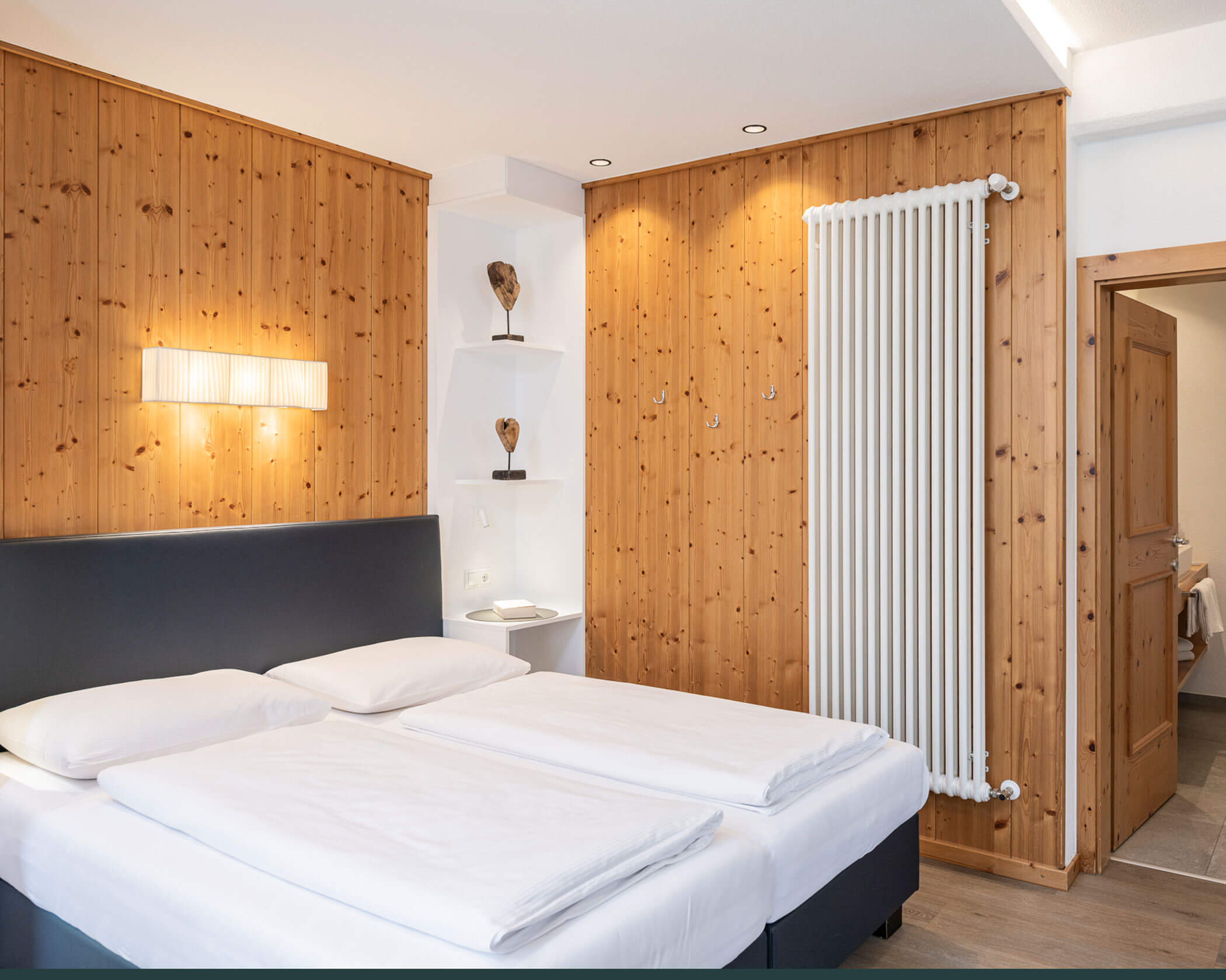 Schlafzimmer mit Doppelbett und schwarzer Rückenlehne im Apartment Typ A - Hotel Anewandter