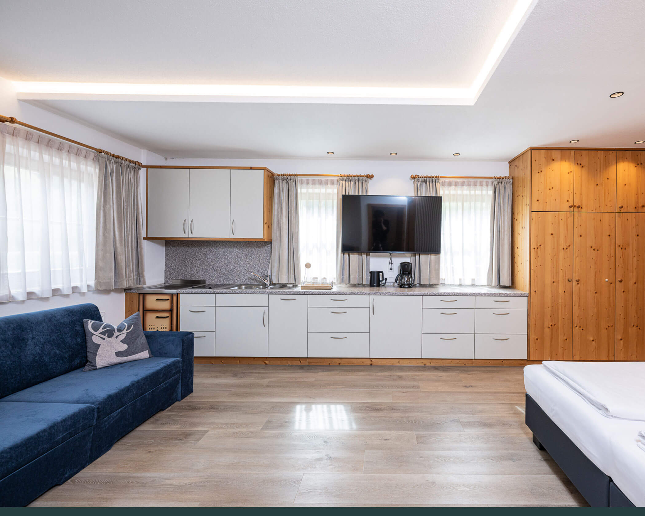 Große Küche mit TV, Sofa und Holzschrank im Apartment Typ A - Hotel Anewandter
