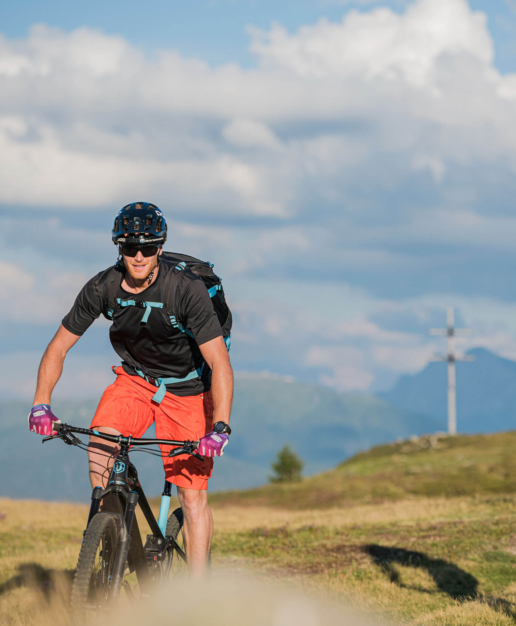 A mountain biker in front of a summit cross - Hotel Anewandter