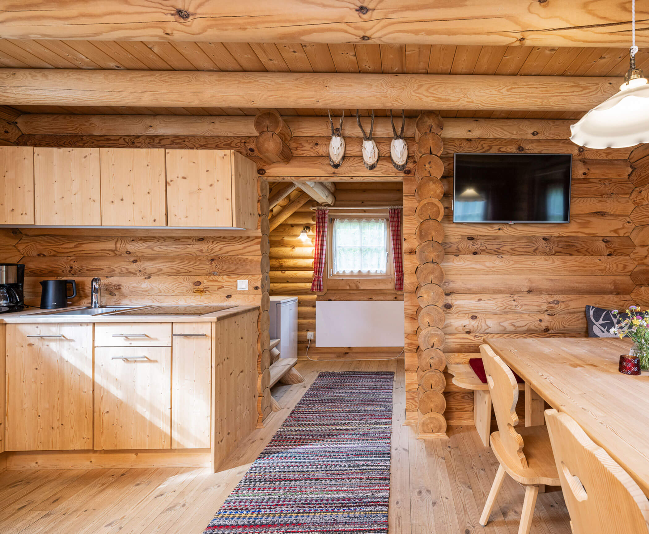 Küche und daneben ein Esstisch im Blockhaus - Hotel Anewandter