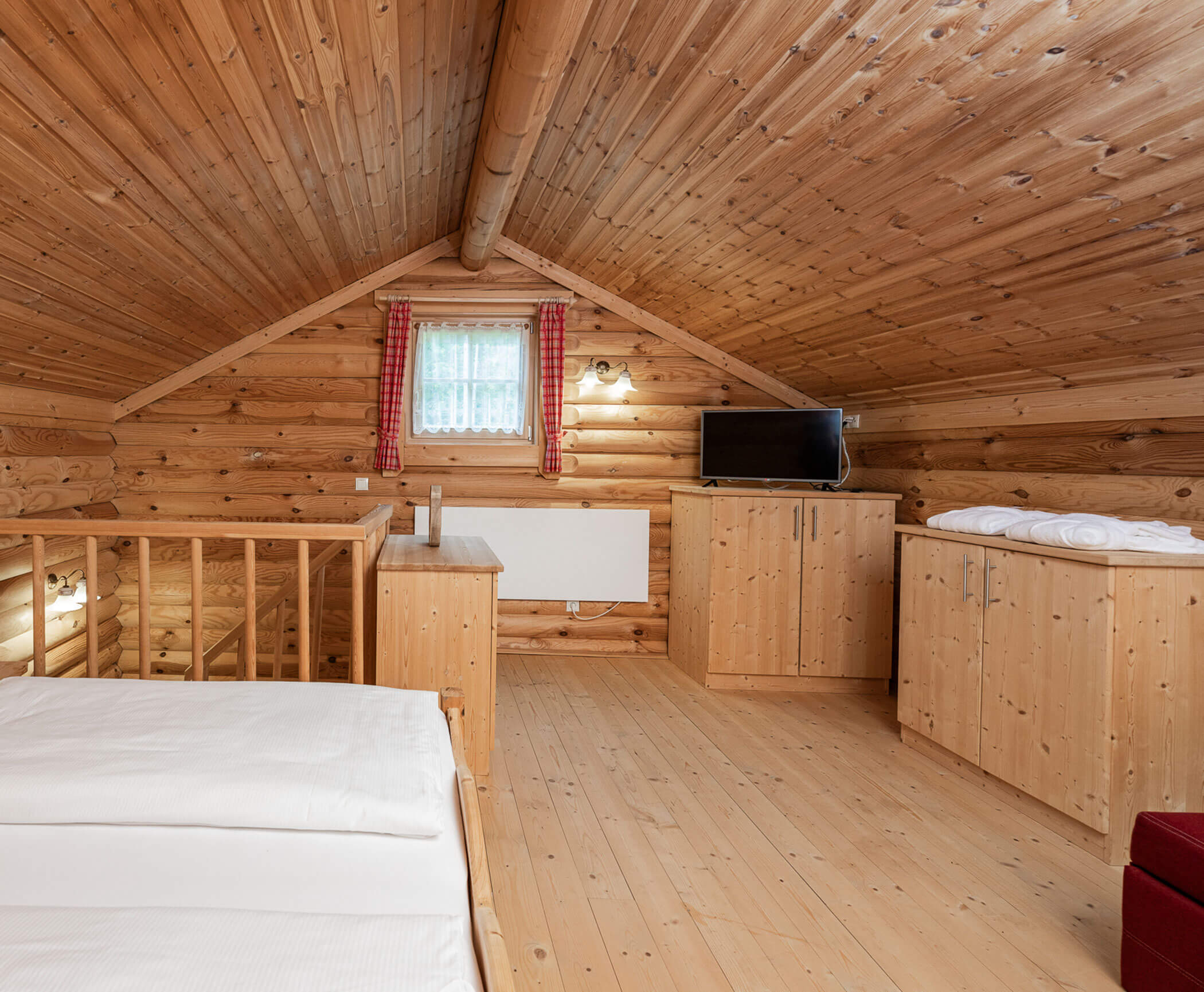 Schlafbereich mit Bett und TV im Blockhaus - Hotel Anewandter