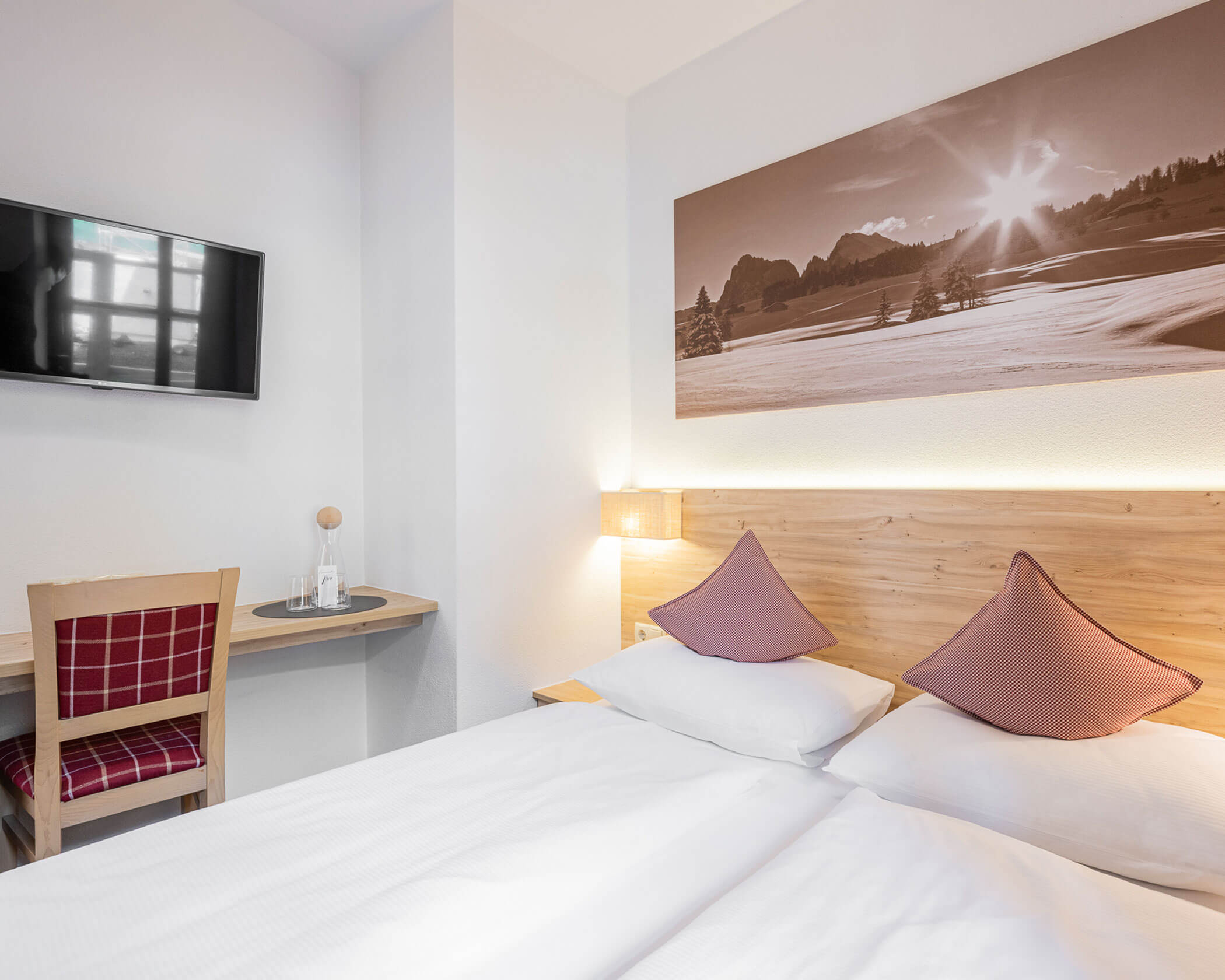 Doppelbett mit Schreibtisch und TV darüber im Doppelzimmer - Hotel Anewandter
