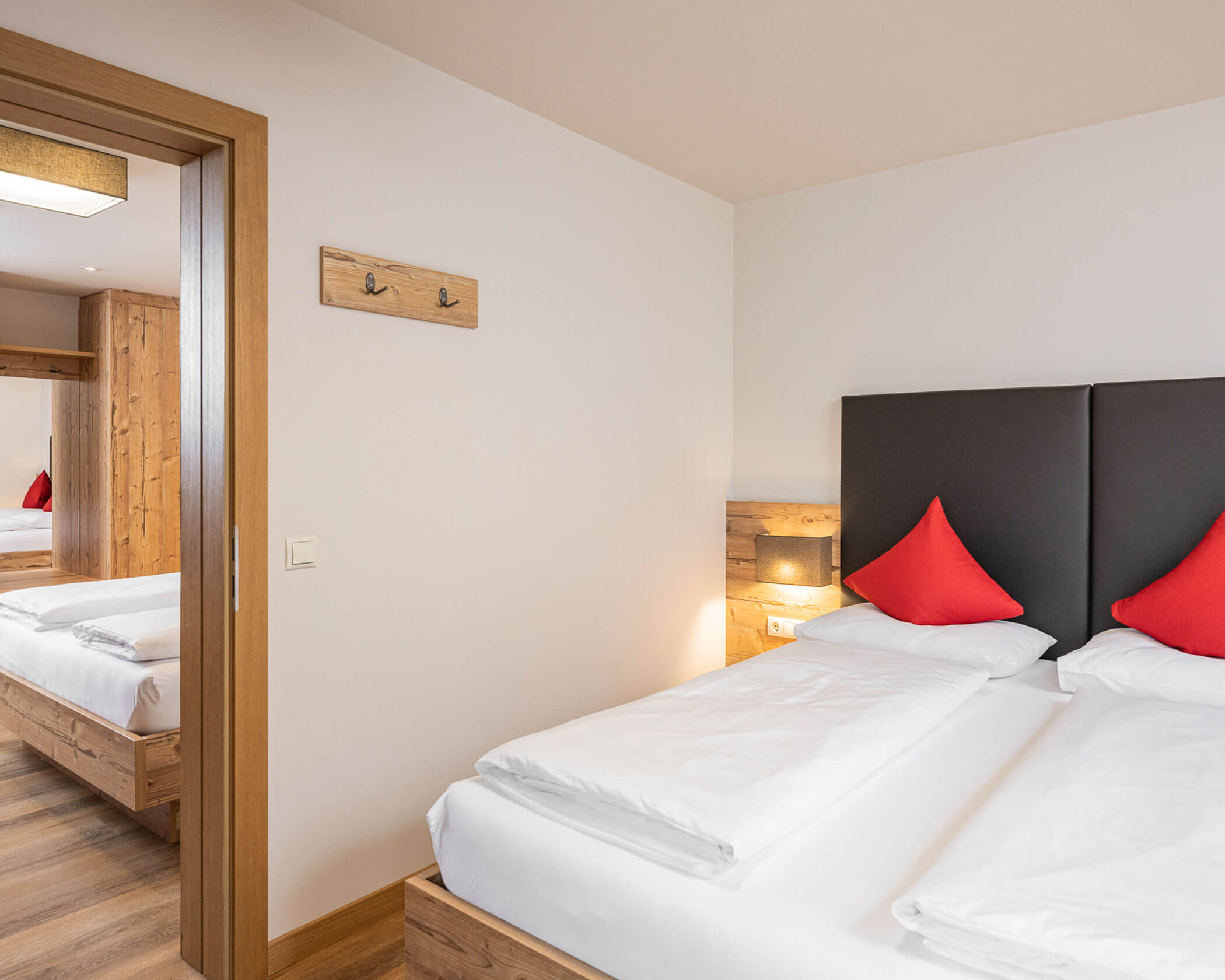 Camera da letto con letto matrimoniale e porta che conduce all'altra camera da letto nella suite familiare - Hotel Anewandter