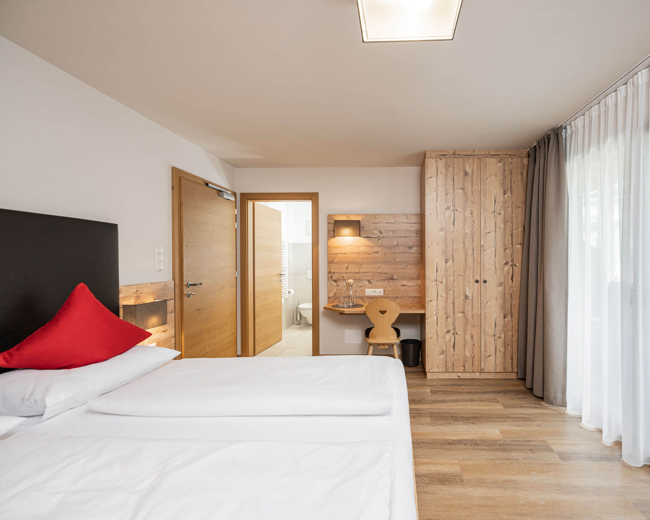 Camera da letto con letto matrimoniale, armadio in legno e scrivania nella suite familiare - Hotel Anewandter