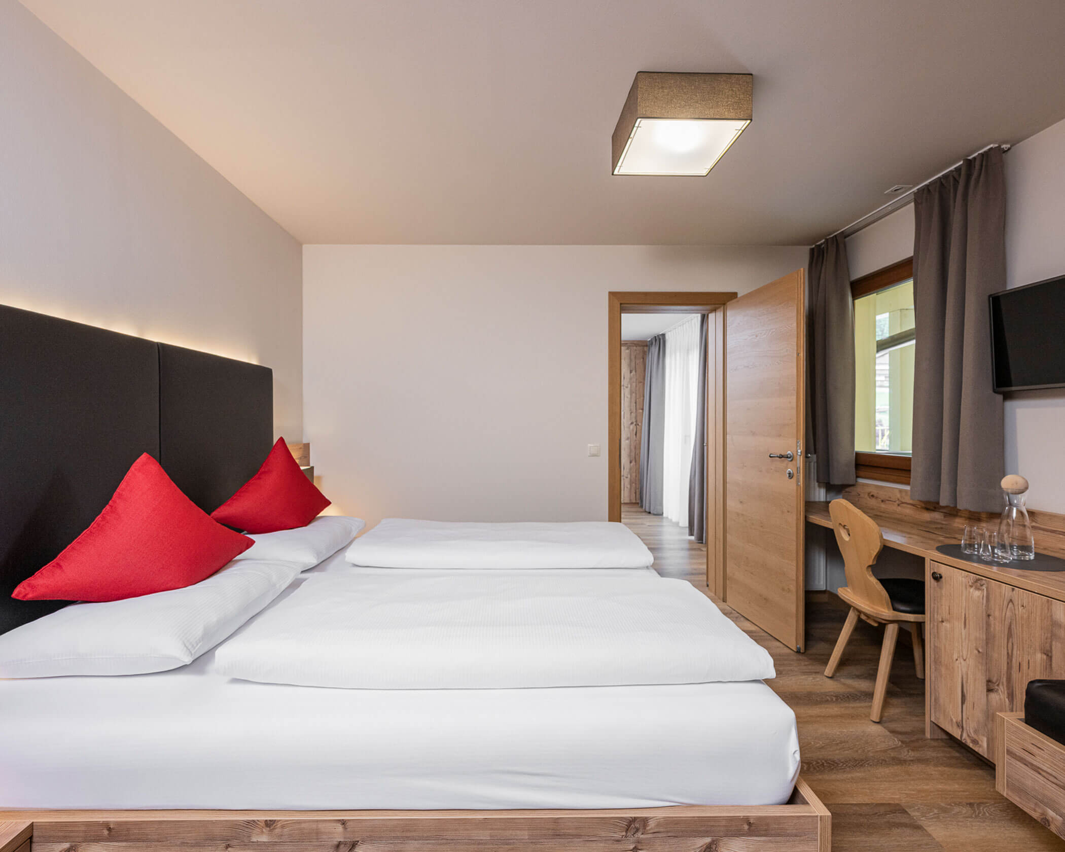 Camera da letto con letto matrimoniale, scrivania e TV nella suite familiare - Hotel Anewandter