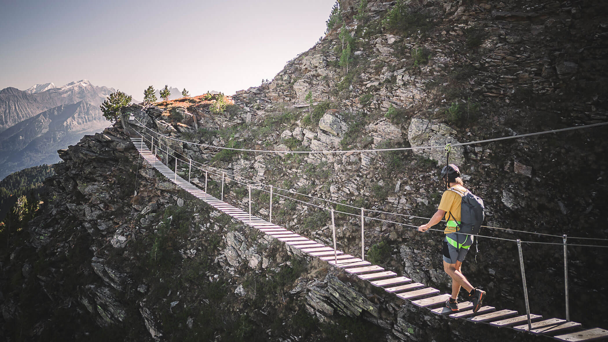 Ein Mann überquert die Brücke vom Gal Klettersteig - Hotel Anewandter