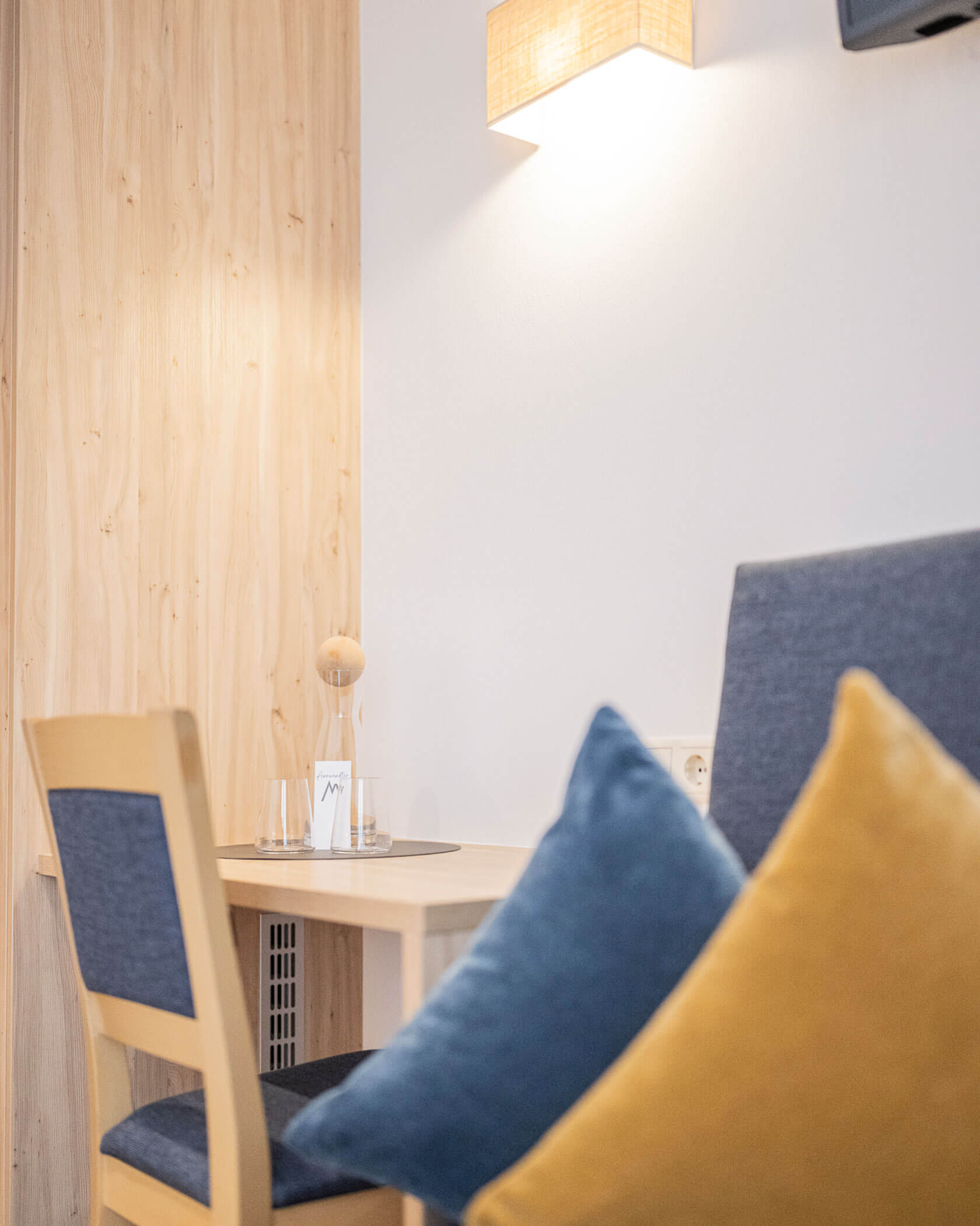 Holztisch mit Stuhl und Sofa daneben - Hotel Anewandter