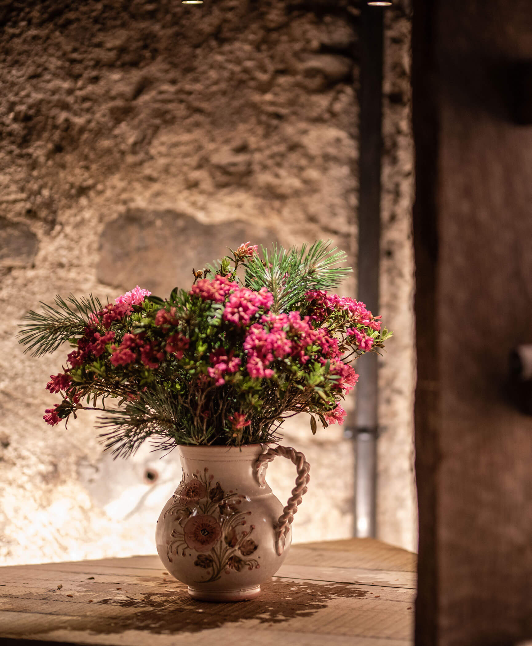 Un vaso pieno di fiori su un tavolo di legno - Hotel Anewandter