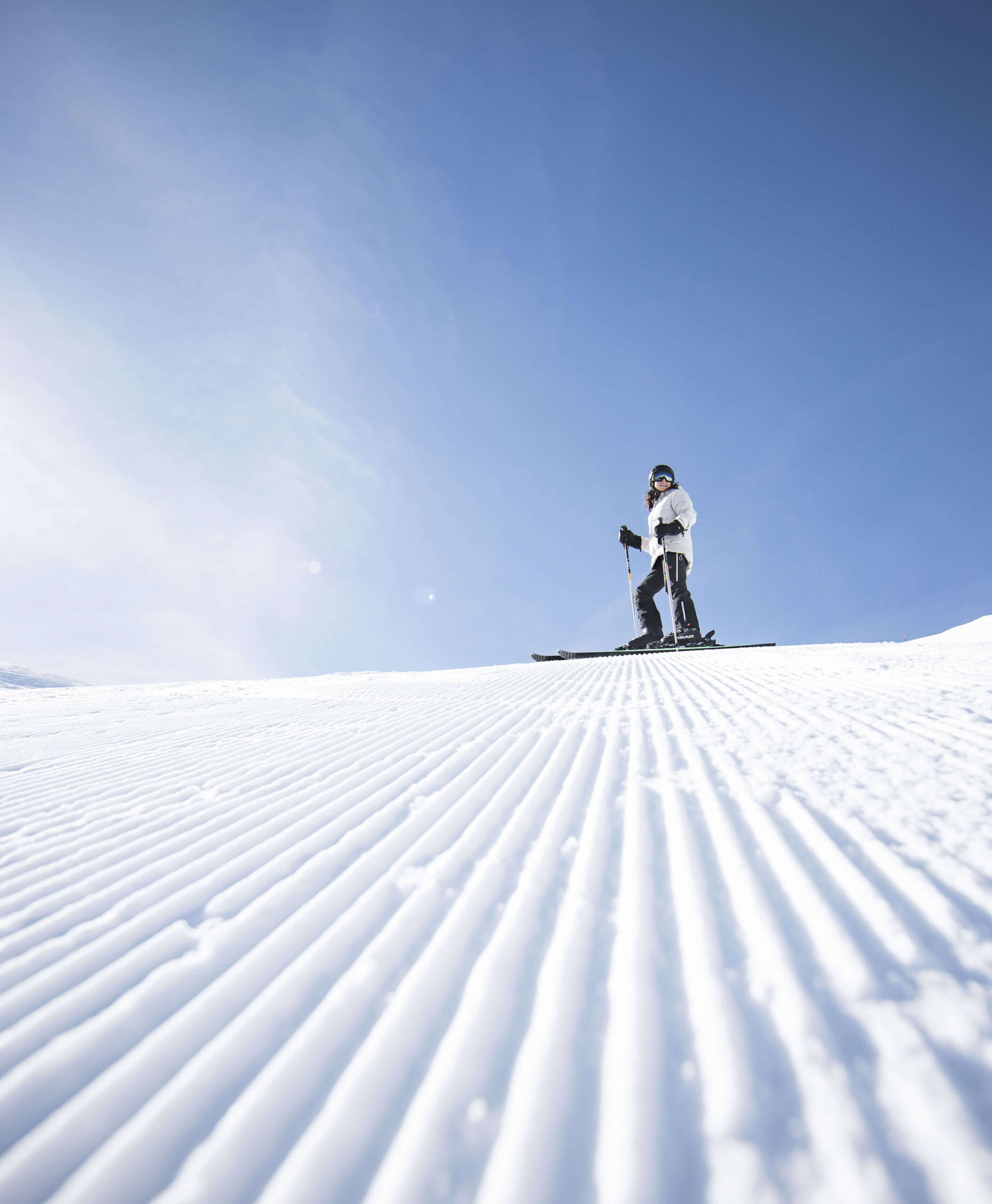 Frau steht mit den Skiern auf den frisch präparierten Pisten - Hotel Anewandter