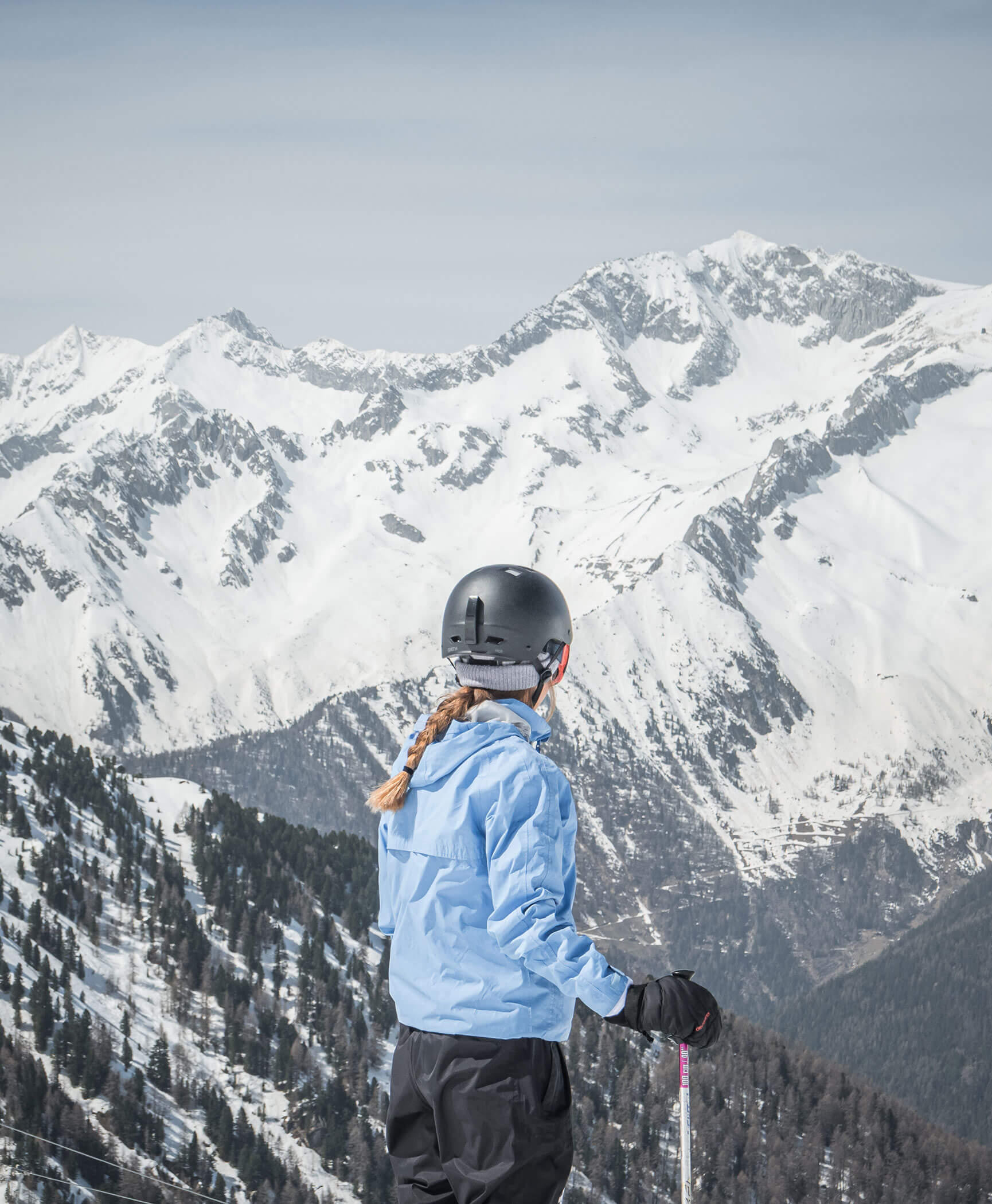 Eine Frau steht mit den Skiern vor den schneebedeckten Bergen - Hotel Anewandter